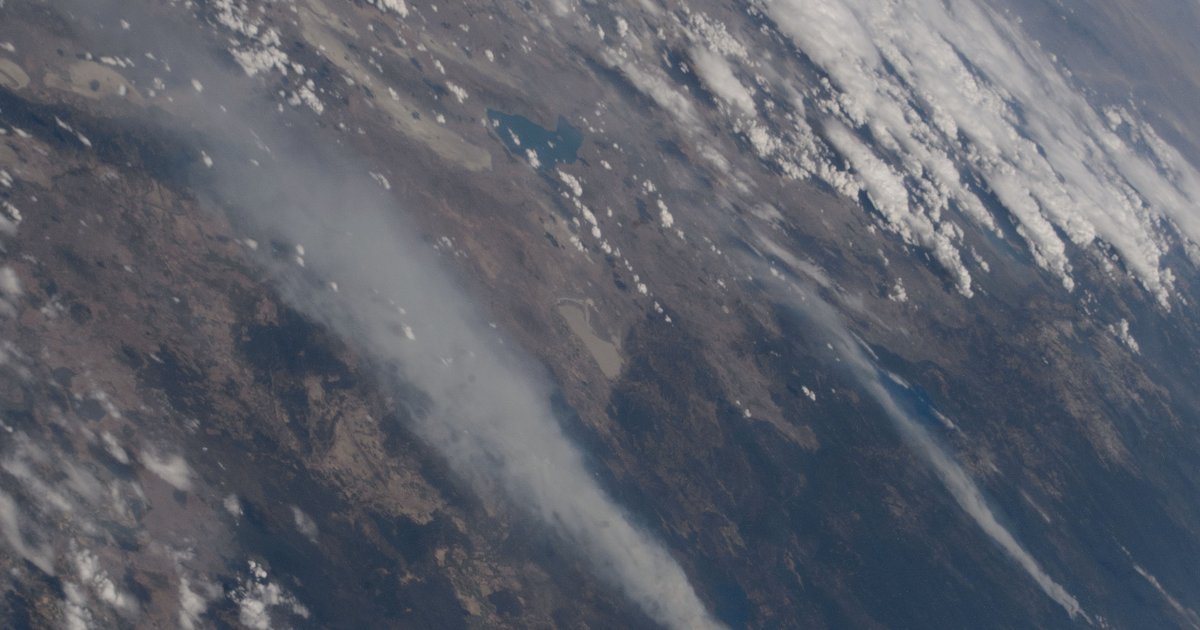 Satellite view of wildfire smoke plumes spreading across the western United States, with orange fire perimeters visible against brown drought-stressed terrain
